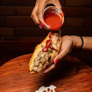 A Gourmet Sandwich Or Hot Dog With Savory Toppings And Sauce. 