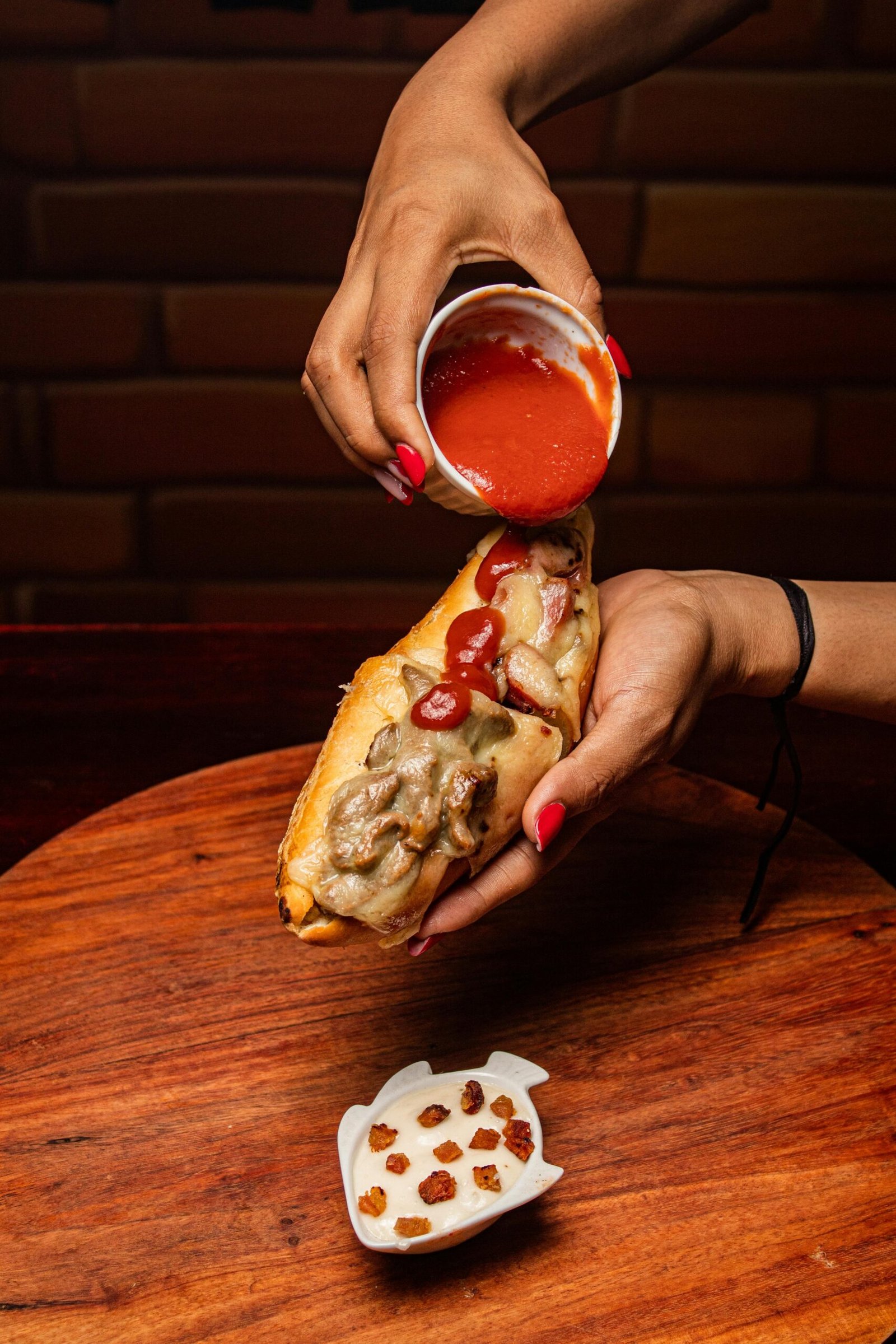 A Gourmet Sandwich Or Hot Dog With Savory Toppings And Sauce.
